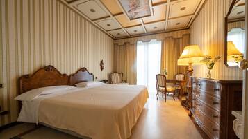 A hotel room with a large bed, a desk with a chair, a dresser, and a mirror.