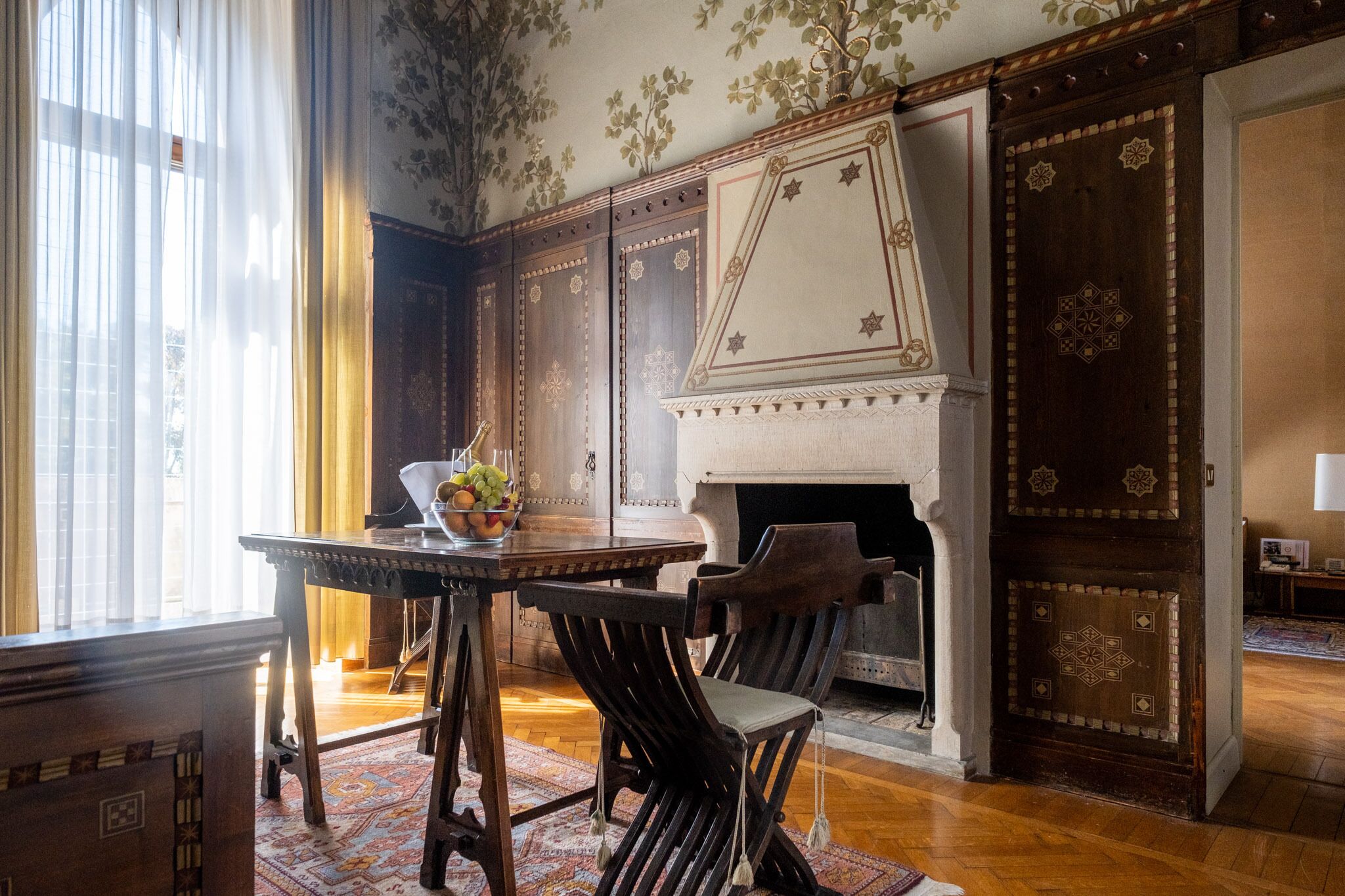 A traditional room with a fireplace, wooden furniture, and patterned wallpaper.