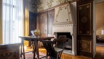 A traditional room with a fireplace, wooden furniture, and patterned wallpaper.