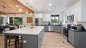Una cocina moderna con una isla grande, electrodomésticos de acero inoxidable y techo de madera.