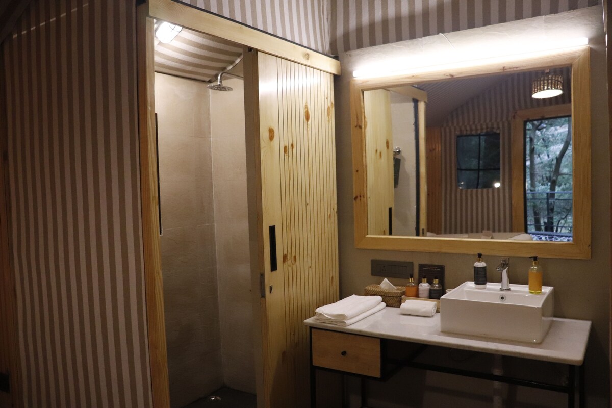 Ein Badezimmer mit einem Holzkosmetikschrank, einem Spiegel, einem Waschbecken und einer Dusche.