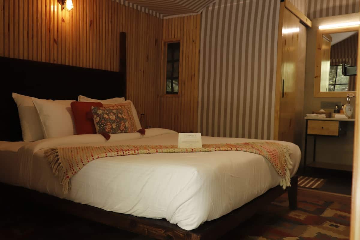 A bed with a headboard, pillows, a blanket, and a bedside table.