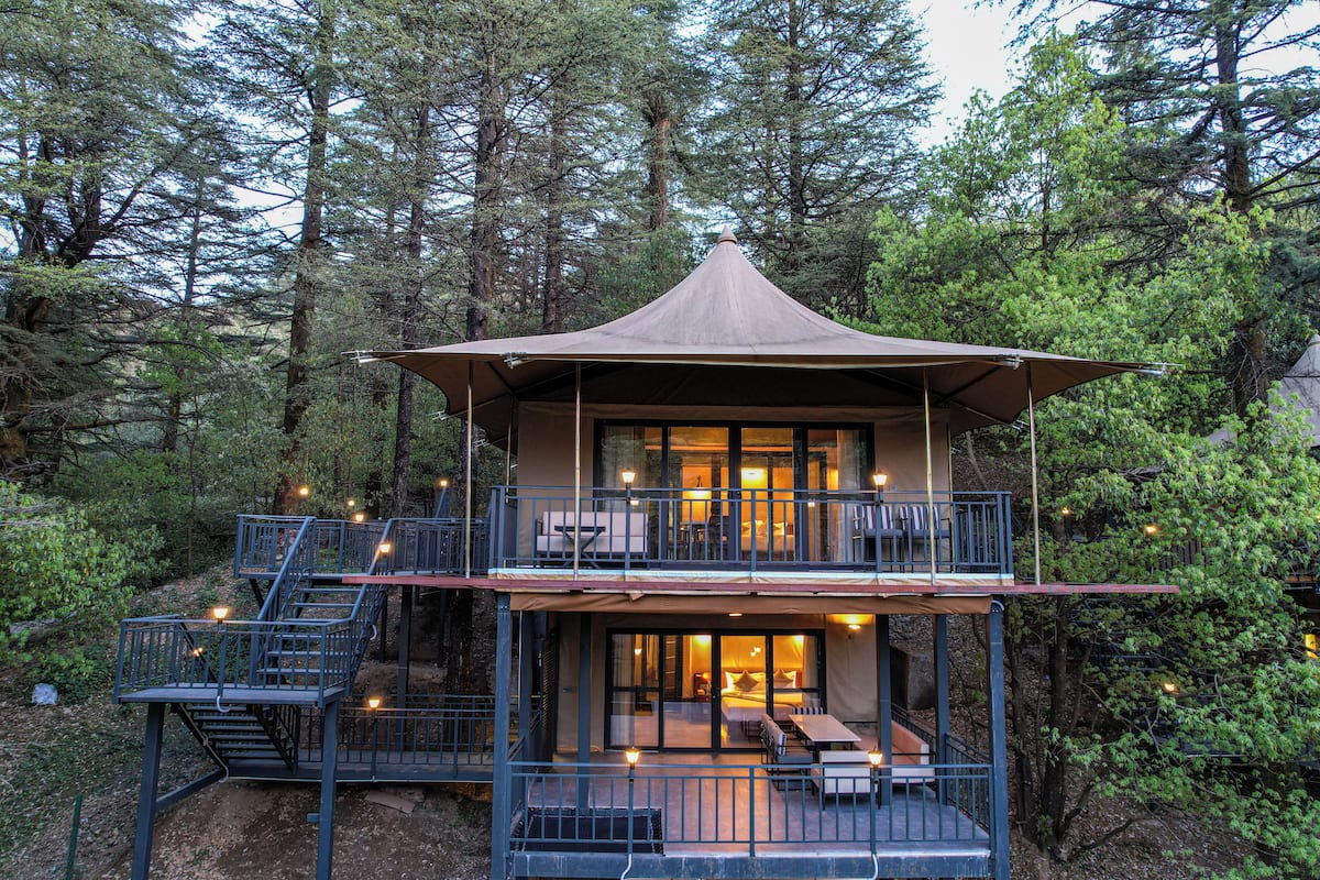 A two-story lodge with a balcony, outdoor seating, and a staircase.
