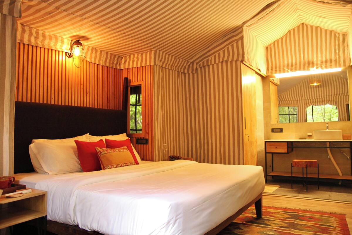 A bedroom with a large bed, a nightstand, a mirror, and a window.