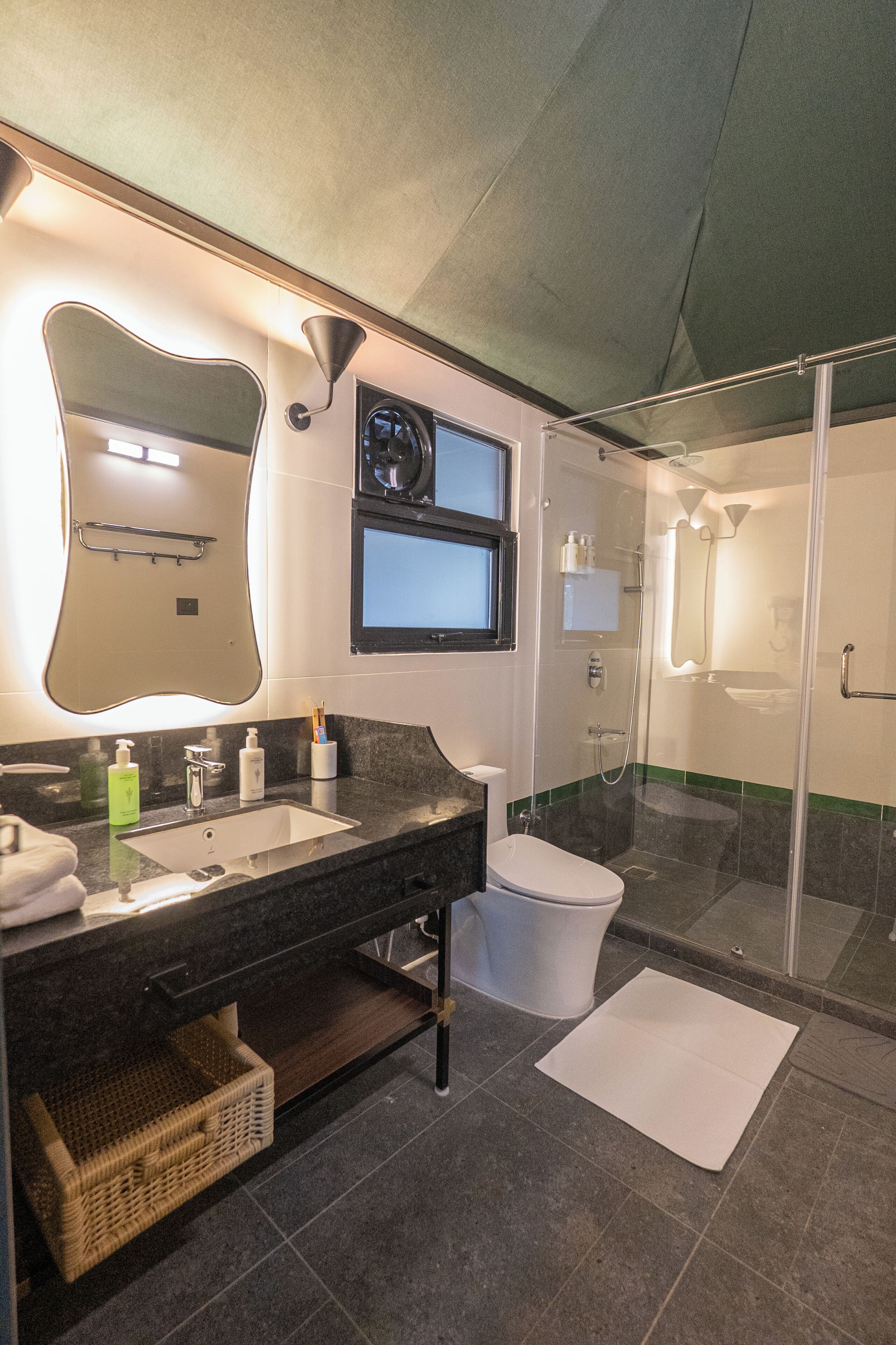 Un baño moderno con un espejo grande, un lavabo, un inodoro y una zona de ducha.
