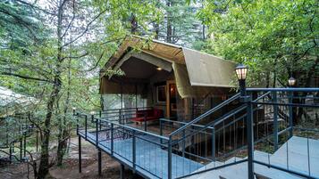 A rustic cabin with a wooden exterior, a covered porch, and a staircase leading to the entrance.