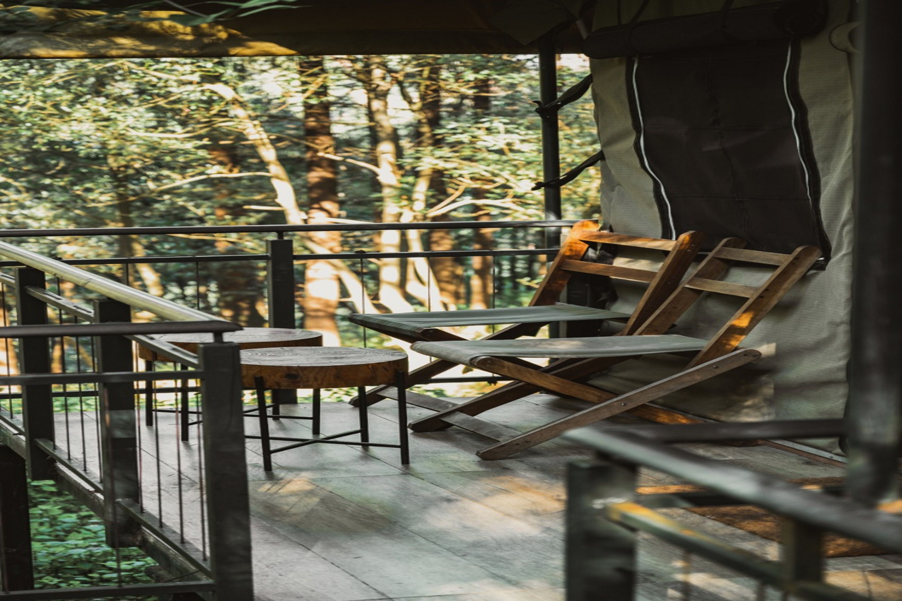 Una terraza de madera con barandilla, una mesa y dos sillas.