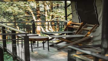 Una terraza de madera con barandilla, una mesa y dos sillas.