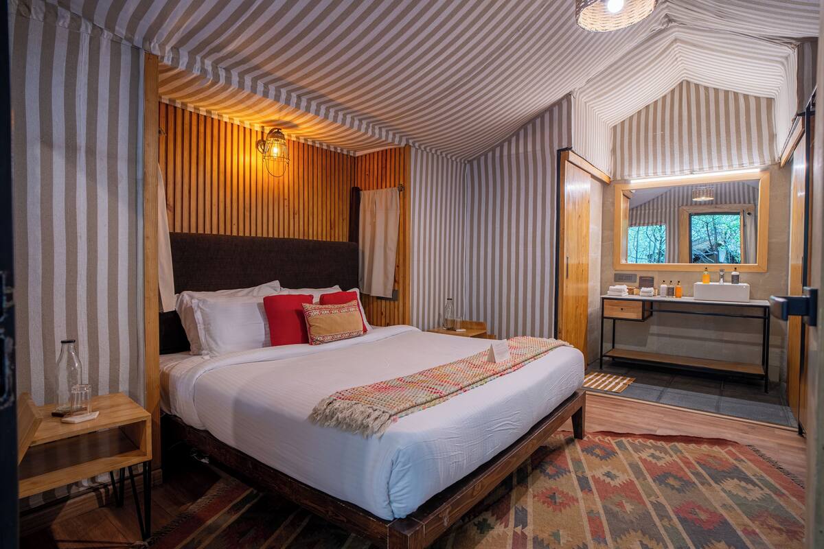 A bedroom with a large bed, wooden headboard, and a bedside table with a glass.