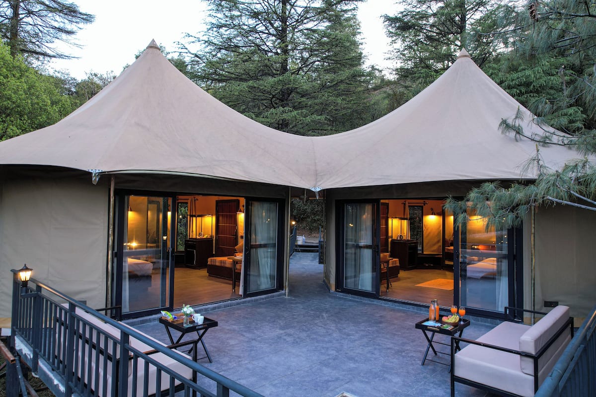Two connected tents with glass doors, a small table with a tray, and a bench.