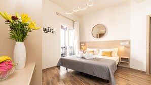 A modern hotel room with a bed, a bedside table, a mirror, and a vase of flowers. - Adeje Plaza (Adeje)