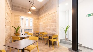 A dining area with wooden tables and yellow chairs, stone walls, and potted plants. - Adeje Plaza (Adeje)