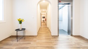 A hallway with a tiled floor, a vase with flowers on a small table, and an elevator. - Adeje Plaza (Adeje)