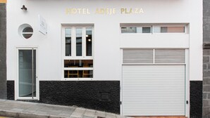 A building with a balcony, a garage door, and a sign that reads "HOTEL ADEJE PLAZA". - Adeje Plaza (Adeje)