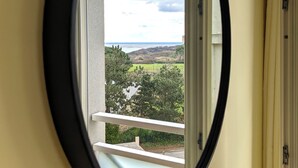 Una ventana con vista a un paisaje que incluye árboles y un cuerpo de agua distante.