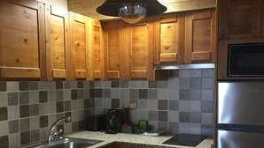 Una cocina con armarios de madera, un refrigerador de acero inoxidable, una cafetera y un microondas.