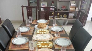 A dining table set with plates, glasses, and a dessert tray. - Rain Homestay (Ambalapuzha)