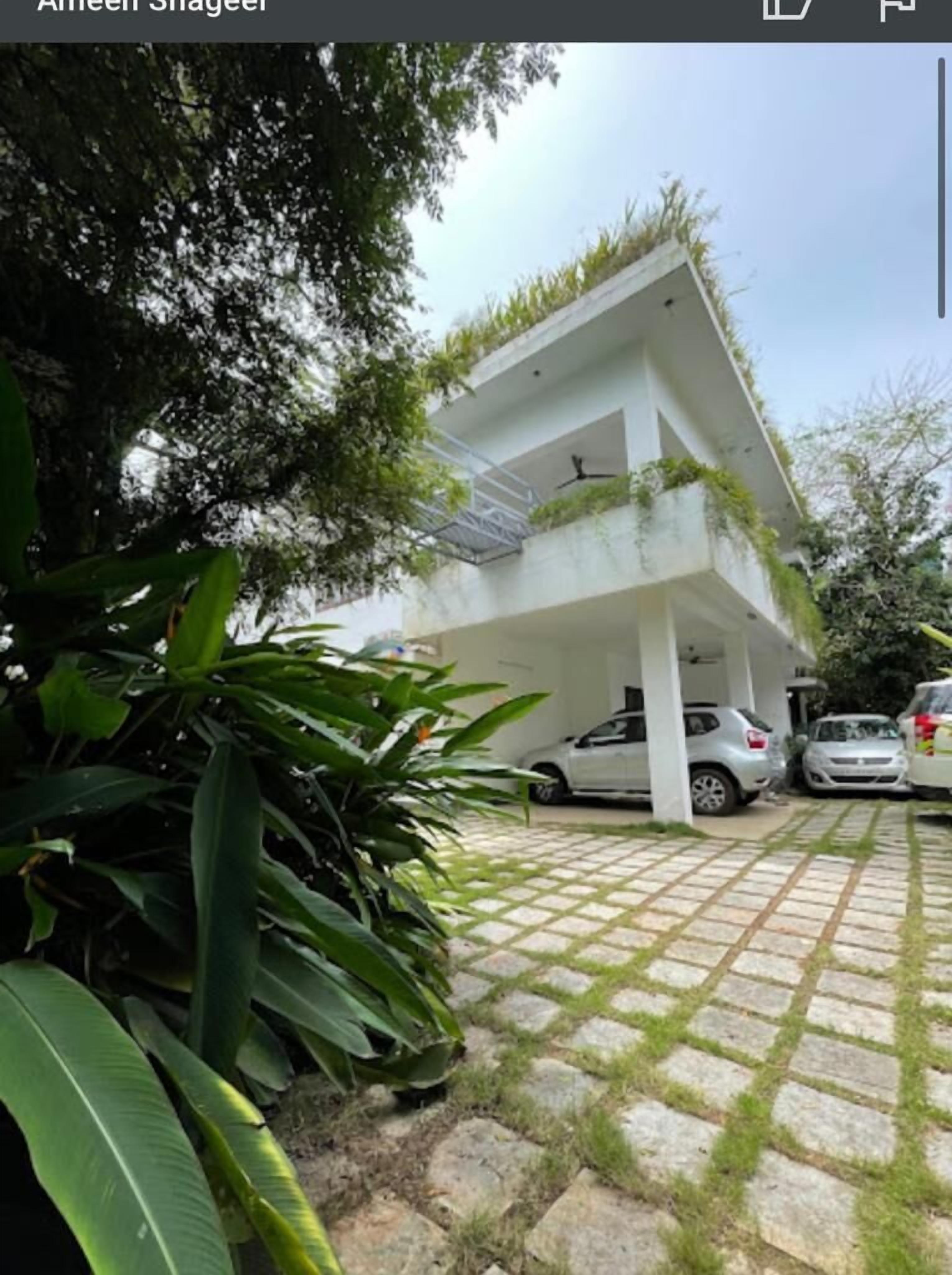 Una moderna casa a due piani con tetto piatto, un ripostiglio coperto e vialetto in pavé.