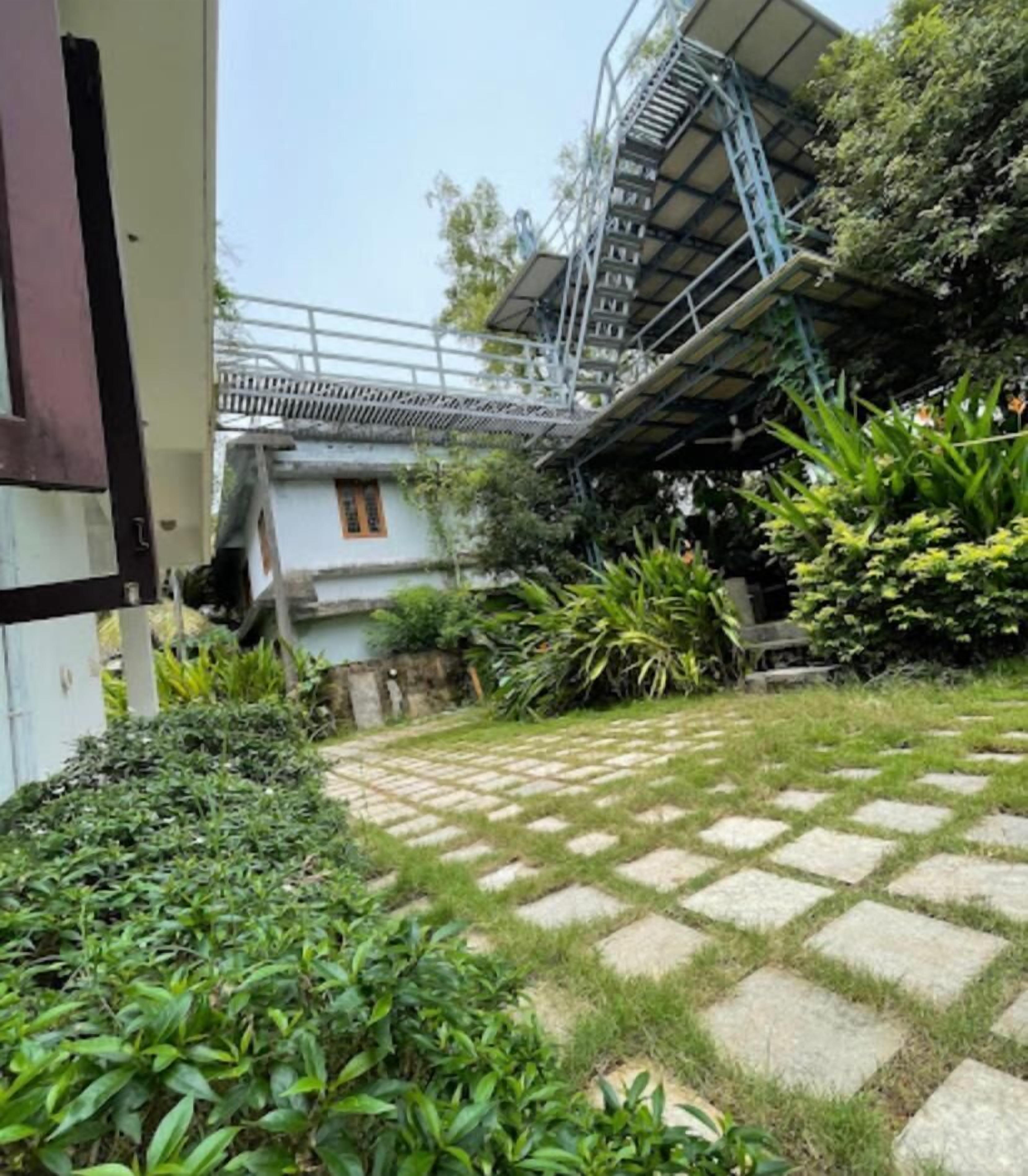 A garden with a stone pathway, a staircase, and a building with a balcony.