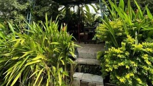 A metal staircase with a roof structure, surrounded by lush greenery. - Rain Homestay (Ambalapuzha)