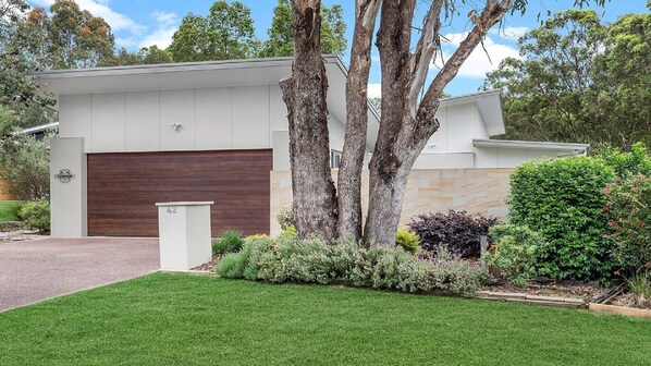 A modern two-story house with a large garage, surrounded by well-maintained lawns and mature trees.