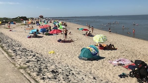 Ein Strand mit Zelten, Sonnenschirmen und Menschen.