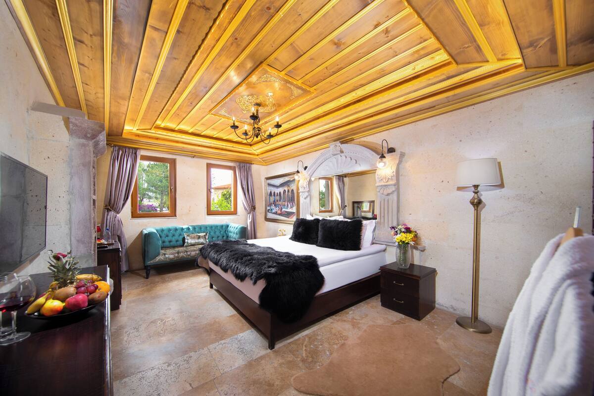 A bedroom with a wooden ceiling, a large bed, a dresser, a mirror, and a floor lamp.
