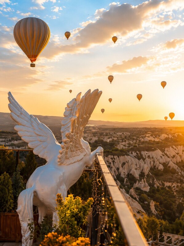 A white angel statue with outstretched wings overlooking a landscape with hot air balloons in the sky. - Cappadocia Pegasos Cave Suite Hotel  (Nevsehir)