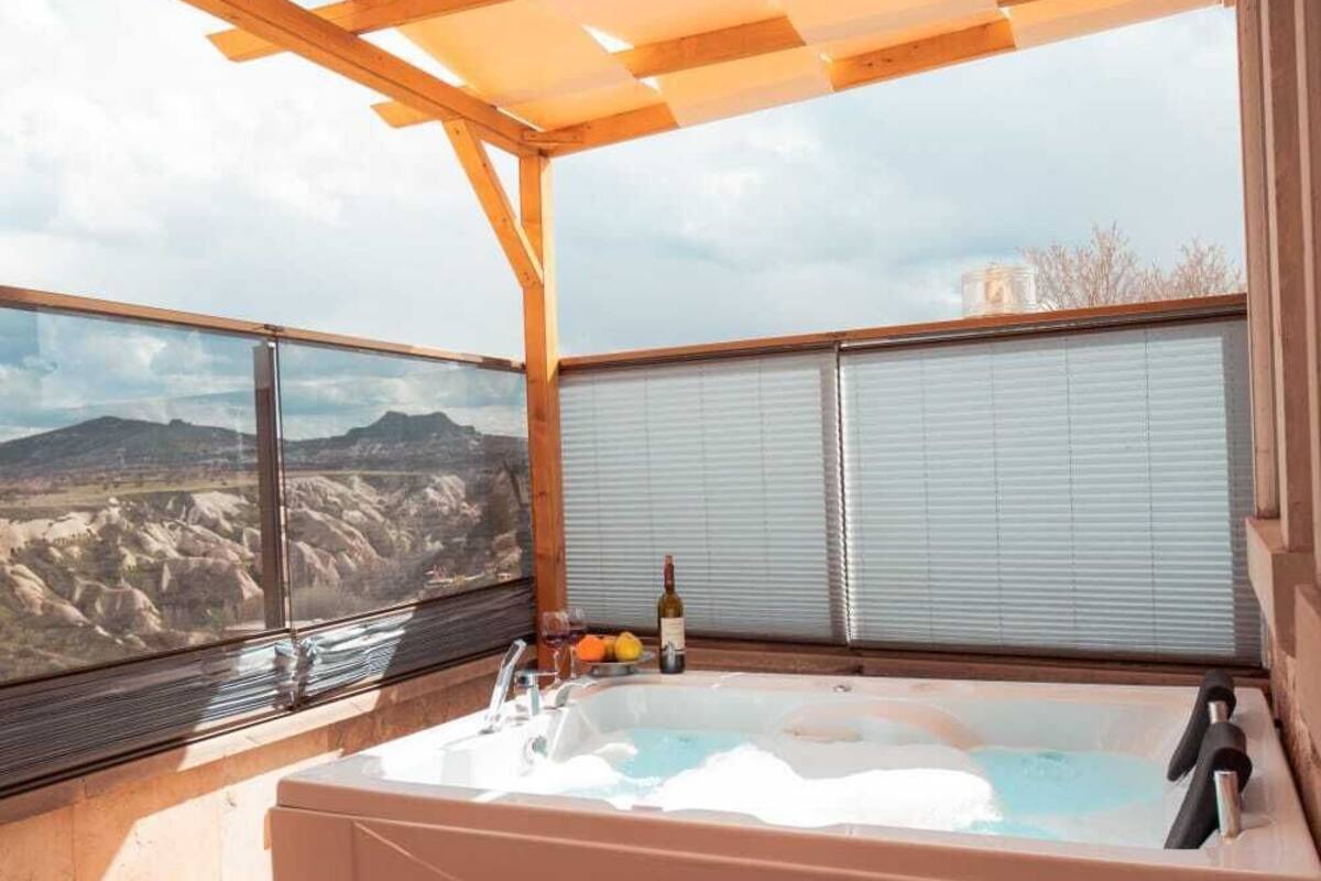 A hot tub under a wooden pergola with a view of mountains.