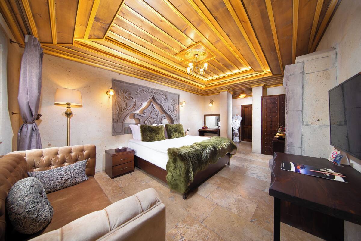 A bedroom with a bed, a sofa, a desk, and a television.