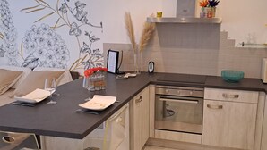 A modern kitchen with a dark countertop, stainless steel appliances, and a built-in washing machine. - Les Arcades Studio in the heart of town, near Puy du Fou, with Wi-fi, Netflix, Canal+. (Cholet)
