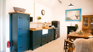 A kitchen with blue cabinets, a wooden countertop, a black refrigerator, and a dining table with chairs. - The Hidden Cottage, Ardara, Donegal. (Ardara)