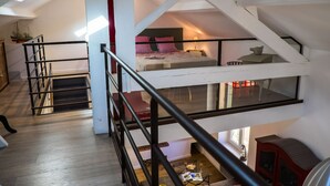 Een meerlaags interieur met een trap, een bed op de bovenverdieping en een rode kast op de benedenverdieping.