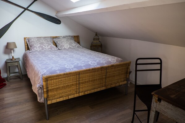 Una camera da letto con un letto, un comodino, una lampada, una sedia e un tavolo in legno.