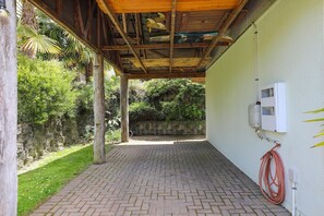 A covered patio area with a brick floor, a wooden ceiling, and a white wall with a utility box. - Millar's Hideaway - Lake Views, Walk to Beach (Rotorua)