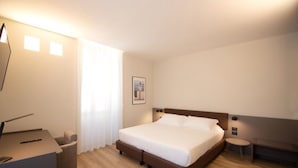 Une chambre d’hôtel avec un grand lit, un bureau, une chaise et une petite table.