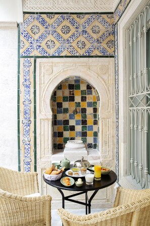 A dining area with a table set for breakfast, featuring bread, pastries, and a fruit drink. - Dar Dorra (Tunis)