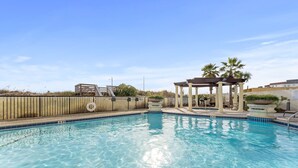 Una piscina blu cristallina con un pontile in legno e un pergolato.