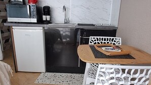 Cocina compacta equipada con refrigerador, microondas, cafetera y pileta.