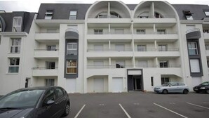 Un edificio de varios pisos con un patio central, balcones y un área de estacionamiento.