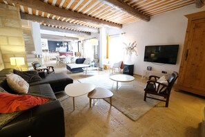 A spacious living room with a black leather sofa, a wooden coffee table, and a TV mounted on the wall. - Vacation rental with pool CHEVAL BLANC LS2-413 (Cheval Blanc)