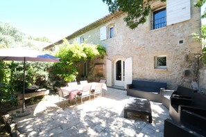 An outdoor patio with stone flooring, a table with chairs, and a sofa. - Vacation rental with pool CHEVAL BLANC LS2-413 (Cheval Blanc)