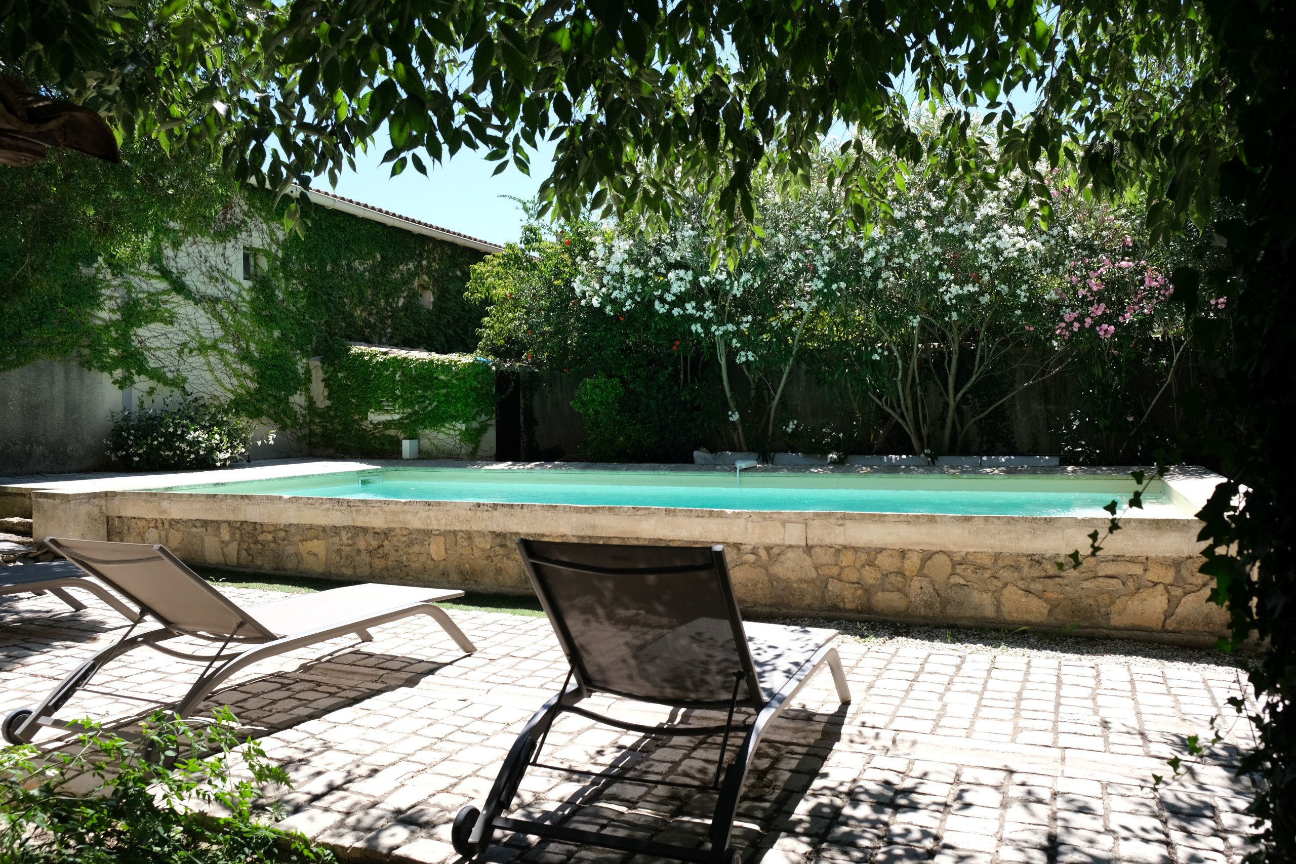 Un espace aménagé au bord de la piscine, avec des chaises longues et un mur en pierre.