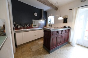 A kitchen with white cabinets, a dark island, and a stainless steel range hood. - Vacation rental with pool CHEVAL BLANC LS2-413 (Cheval Blanc)