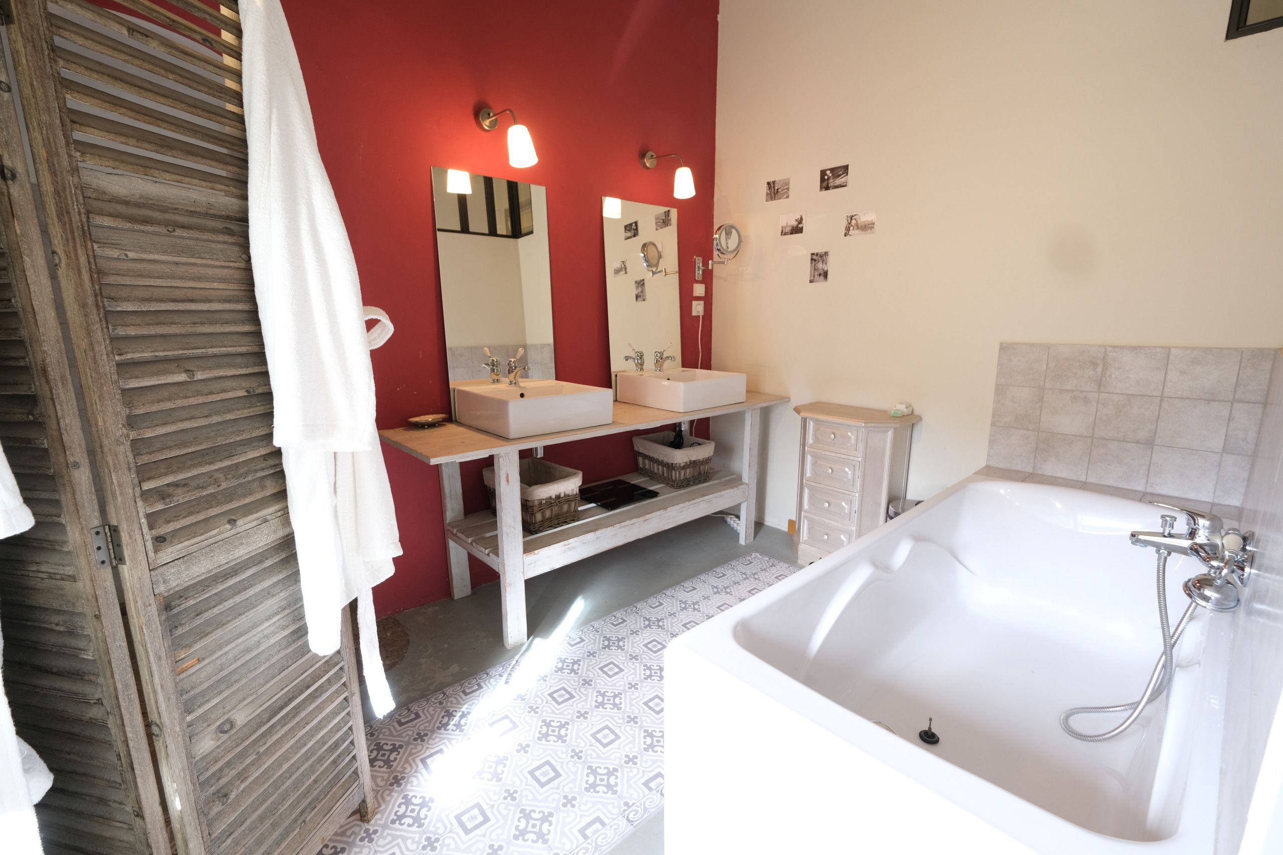Une salle de bain avec une porte en bois, un lavabo blanc, un miroir et une baignoire.