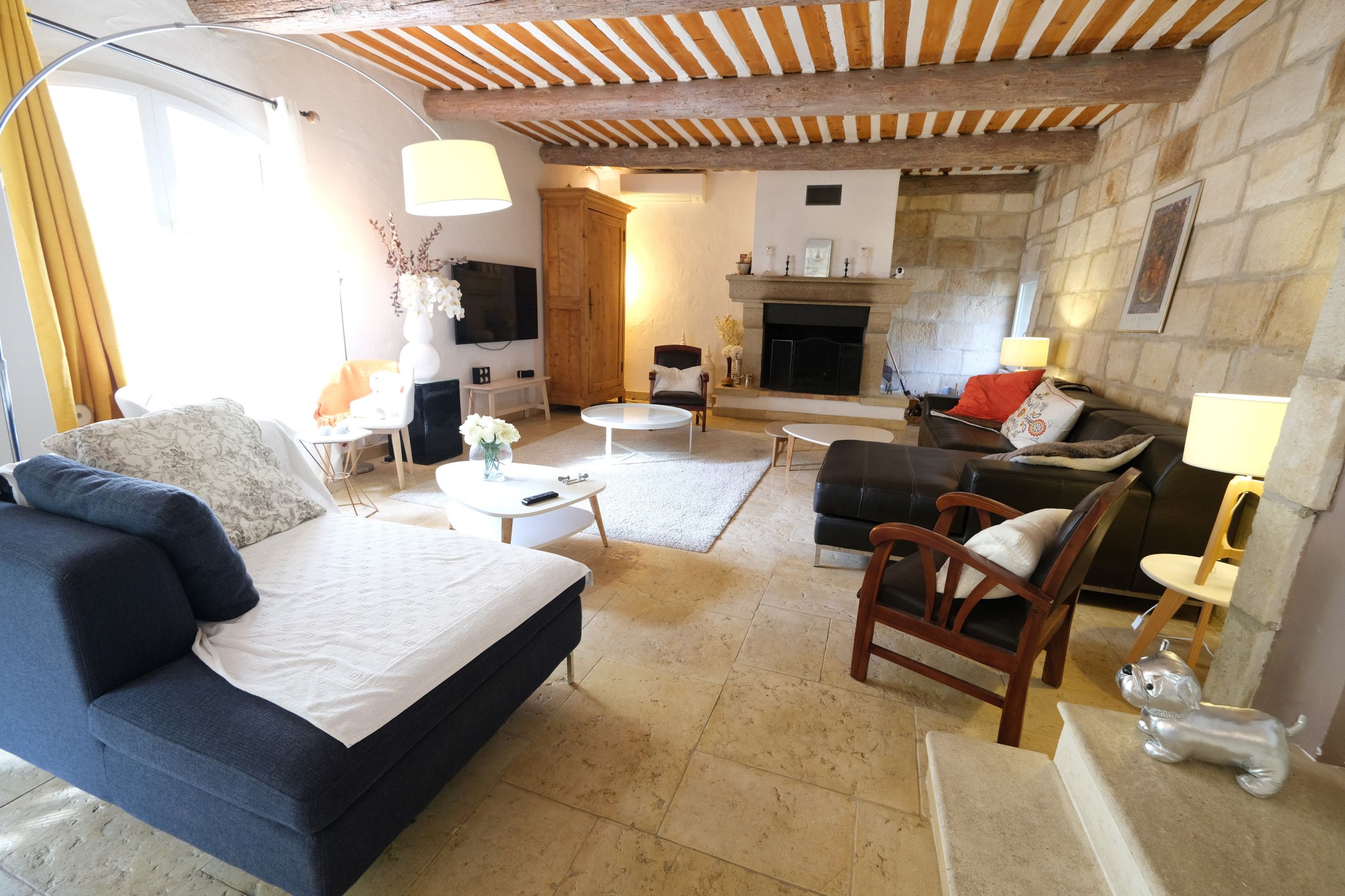 Una sala de estar acogedora con un sofá azul, una silla de madera, una mesita y una chimenea.