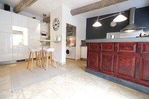 A modern kitchen with white cabinets, a red island, wooden stools, and pendant lighting. - Vacation rental with pool CHEVAL BLANC LS2-413 (Cheval Blanc)