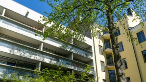 A multi-story building with balconies, large windows, and a tree in the foreground. - Helsinki home by Johanna Gullichsen (Helsinki)