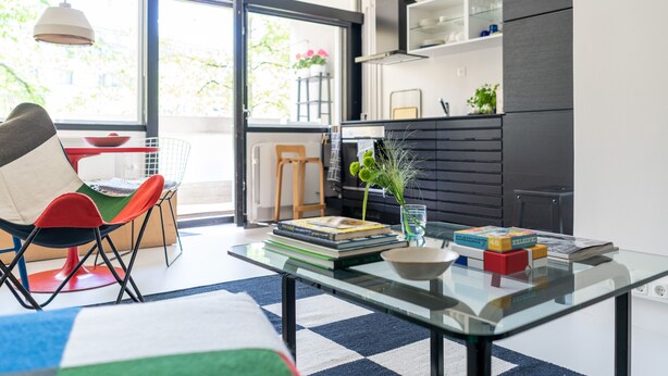 A modern kitchen with a glass table, a red chair, and a view of the outdoors. - Helsinki home by Johanna Gullichsen (Helsinki)