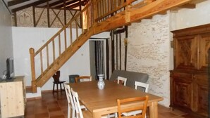 Un comedor con mesa y sillas de madera, una escalera y una pared rústica.